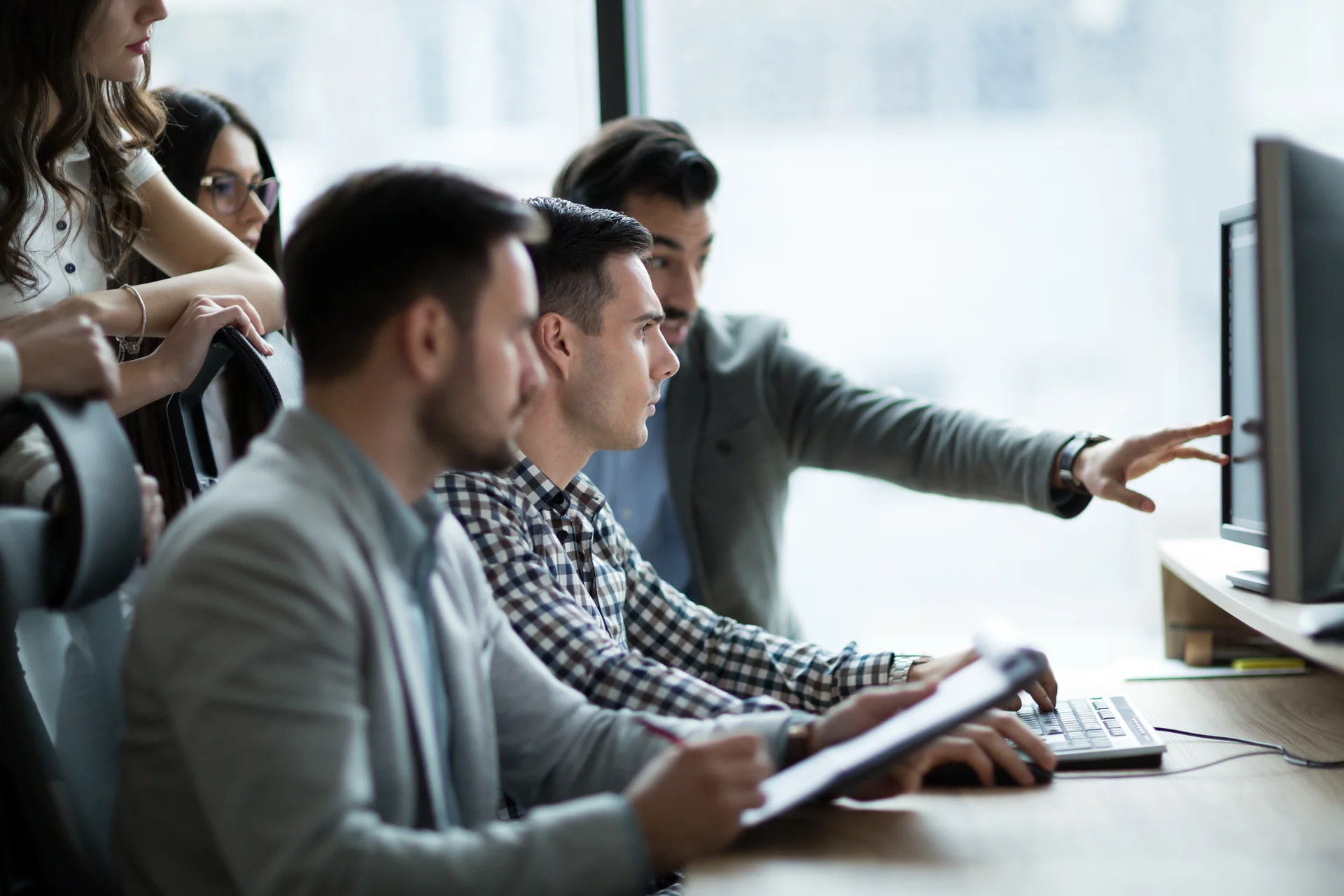 Drei Männer und zwei Frauen schauen auf einen Bildschirm und diskutieren