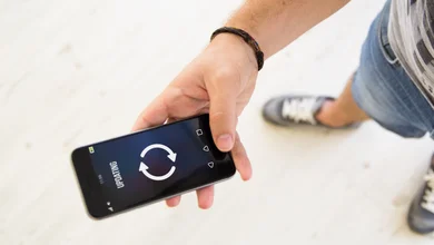 Ein Mann hält ein Handy auf dem ein Upgradingbildschirm zu sehen ist