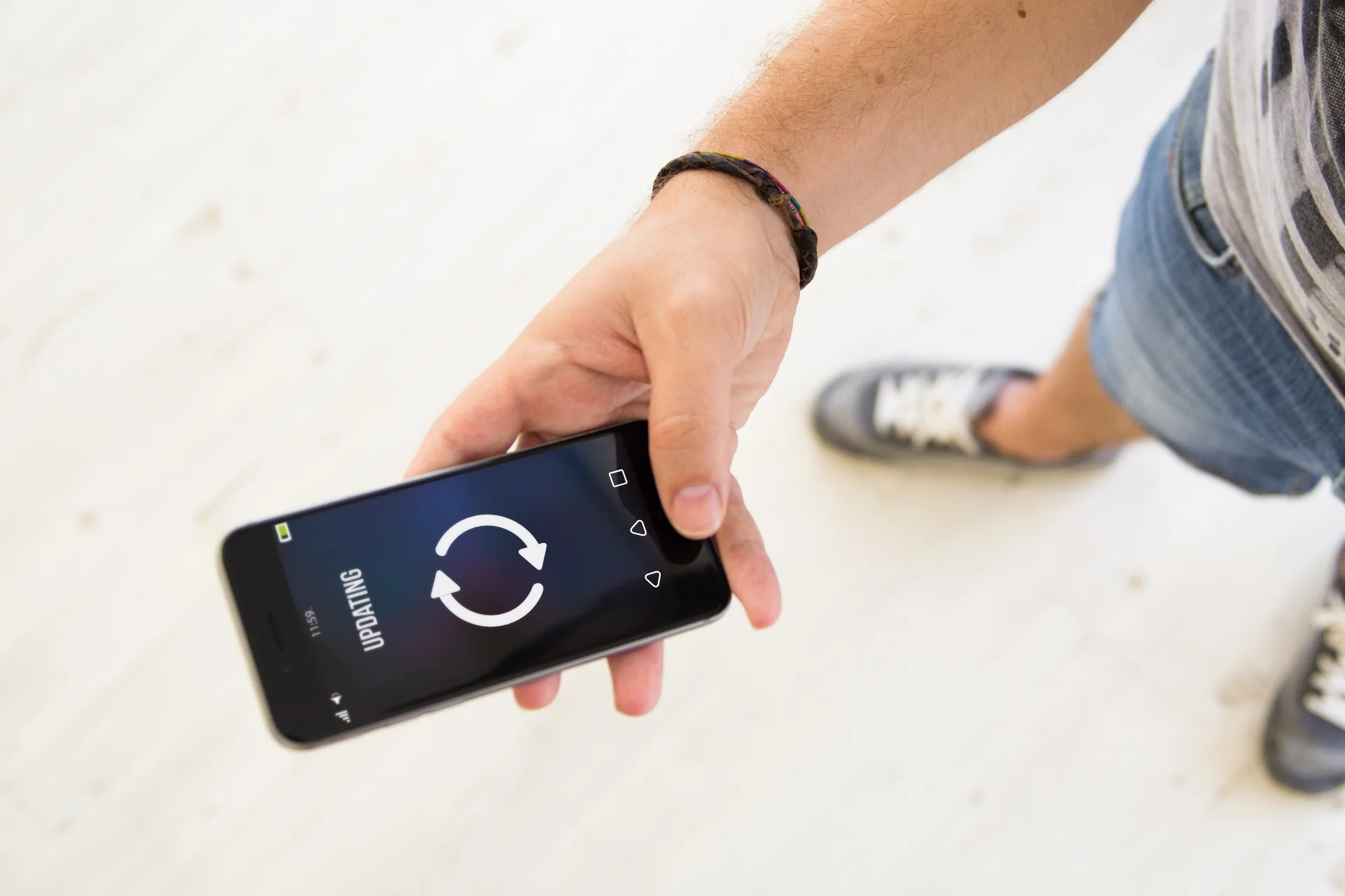 Ein Mann hält ein Handy auf dem ein Upgradingbildschirm zu sehen ist