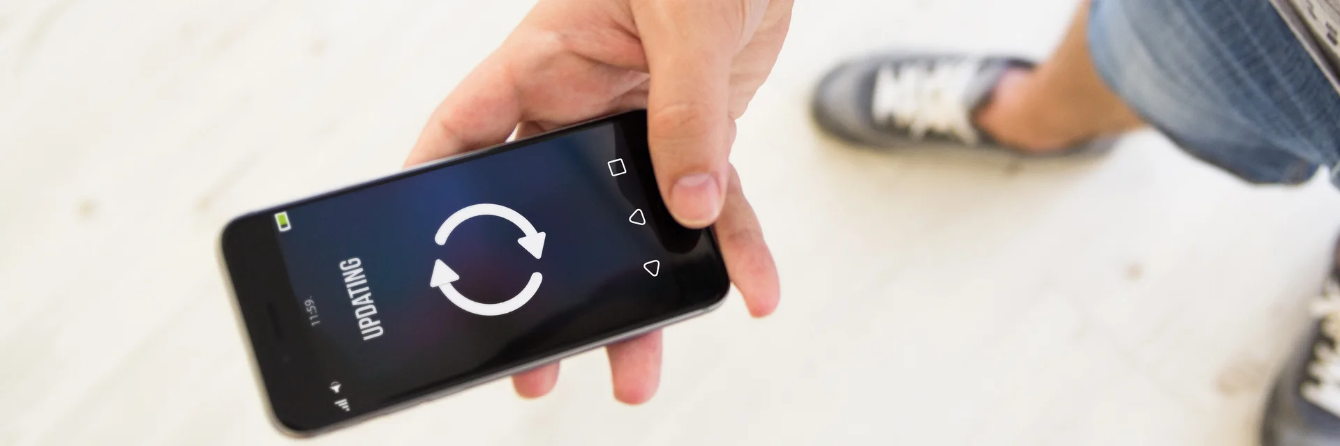 Ein Mann hält ein Handy auf dem ein Upgradingbildschirm zu sehen ist