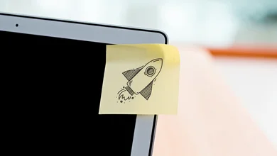 Man sieht die obere rechte Ecke eines Laptops, darauf ist ein Post-It mit einer gezeichneten Rakete